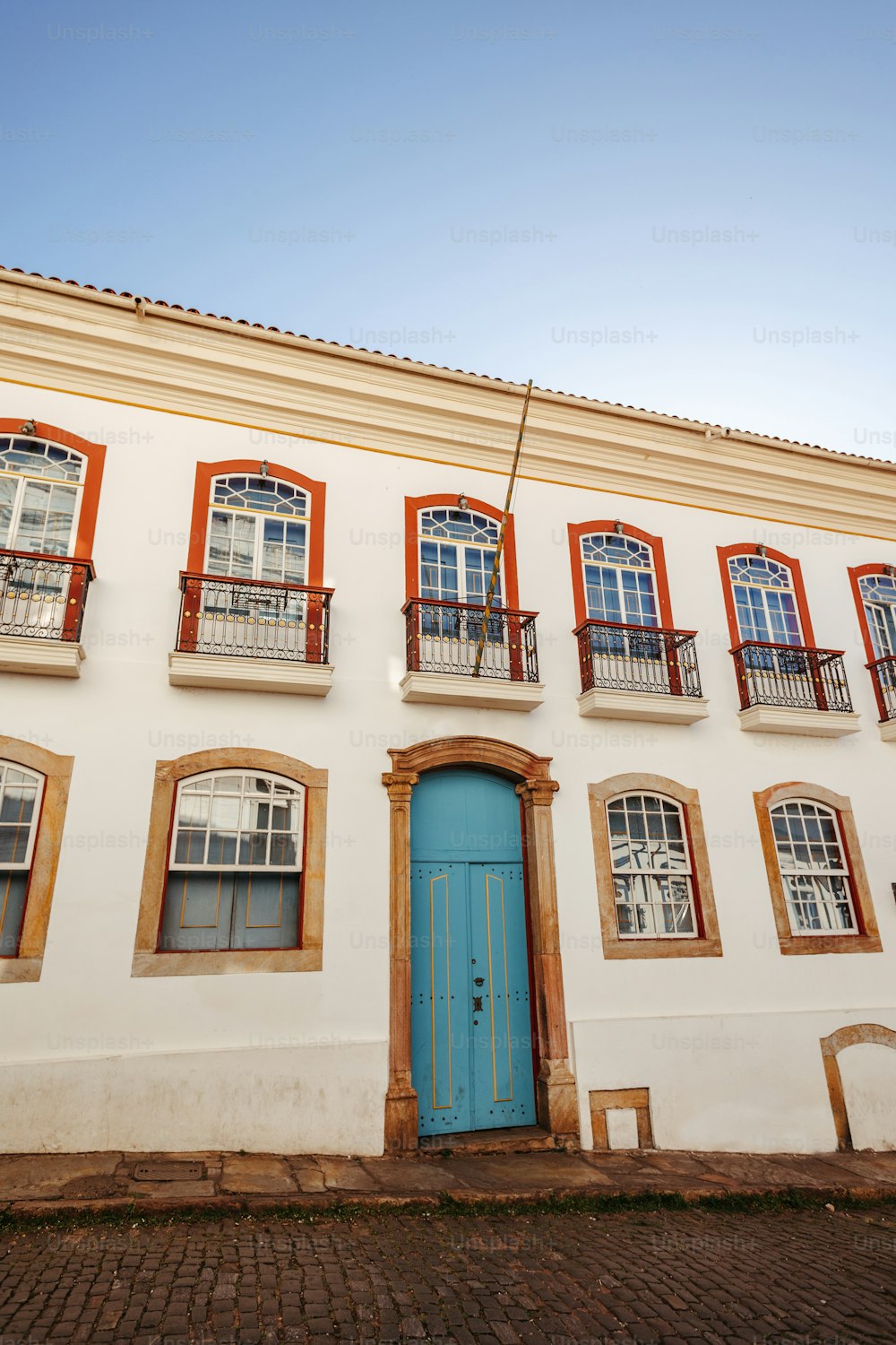 Un edificio blanco con una puerta y ventanas azules