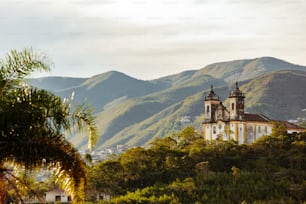 a church in the middle of a forest with mountains in the background