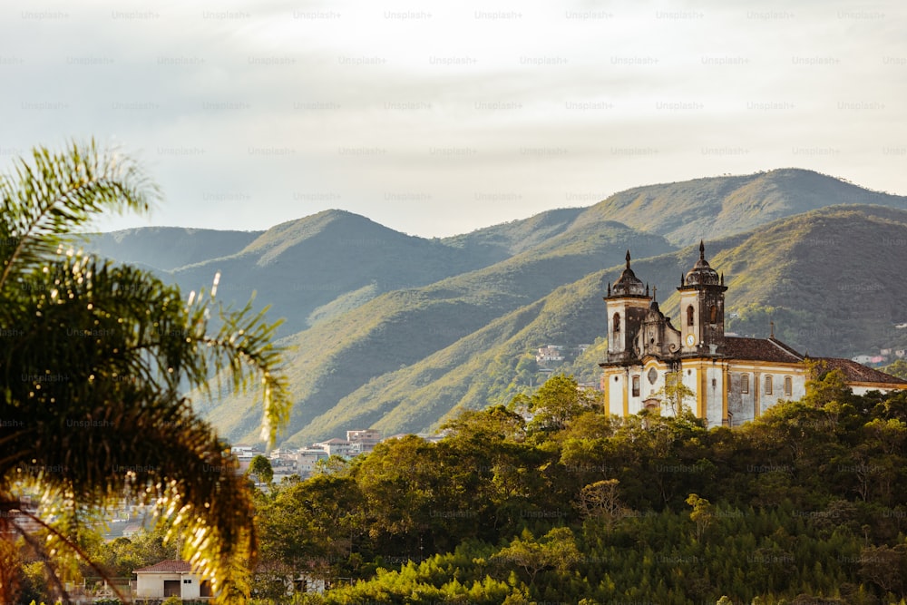 a church in the middle of a forest with mountains in the background