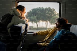 a man and a woman sitting on a bus looking out the window