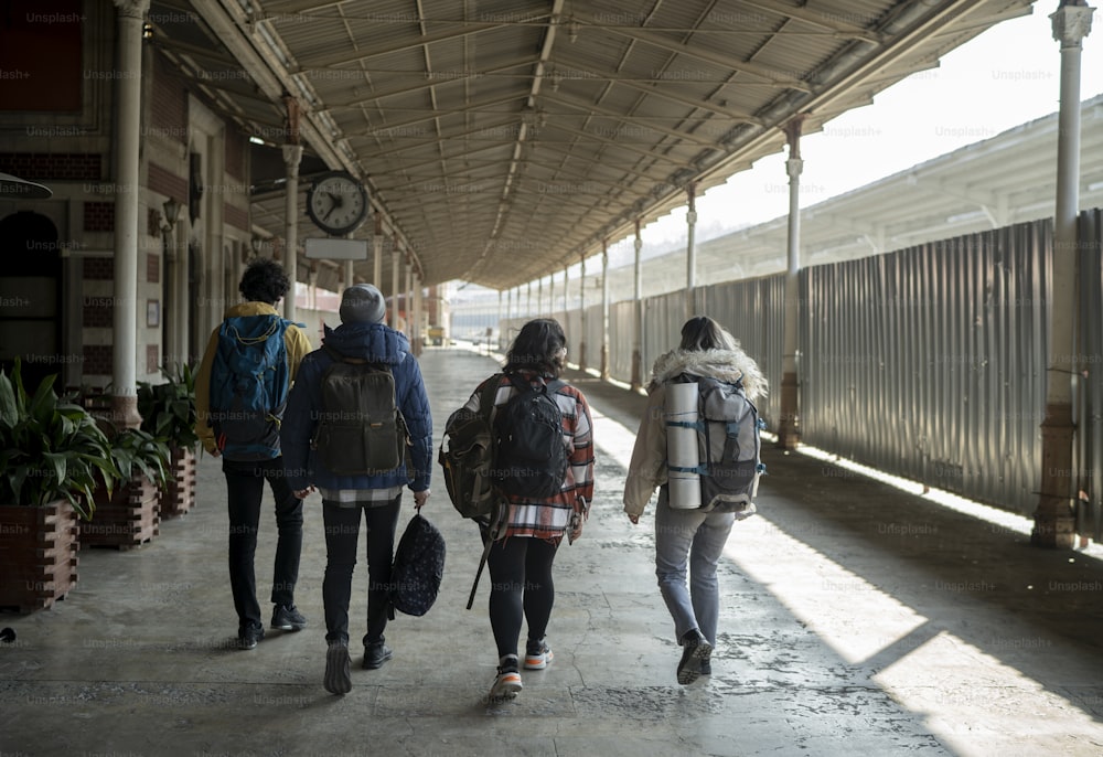 a group of people walking down a sidewalk next to a train