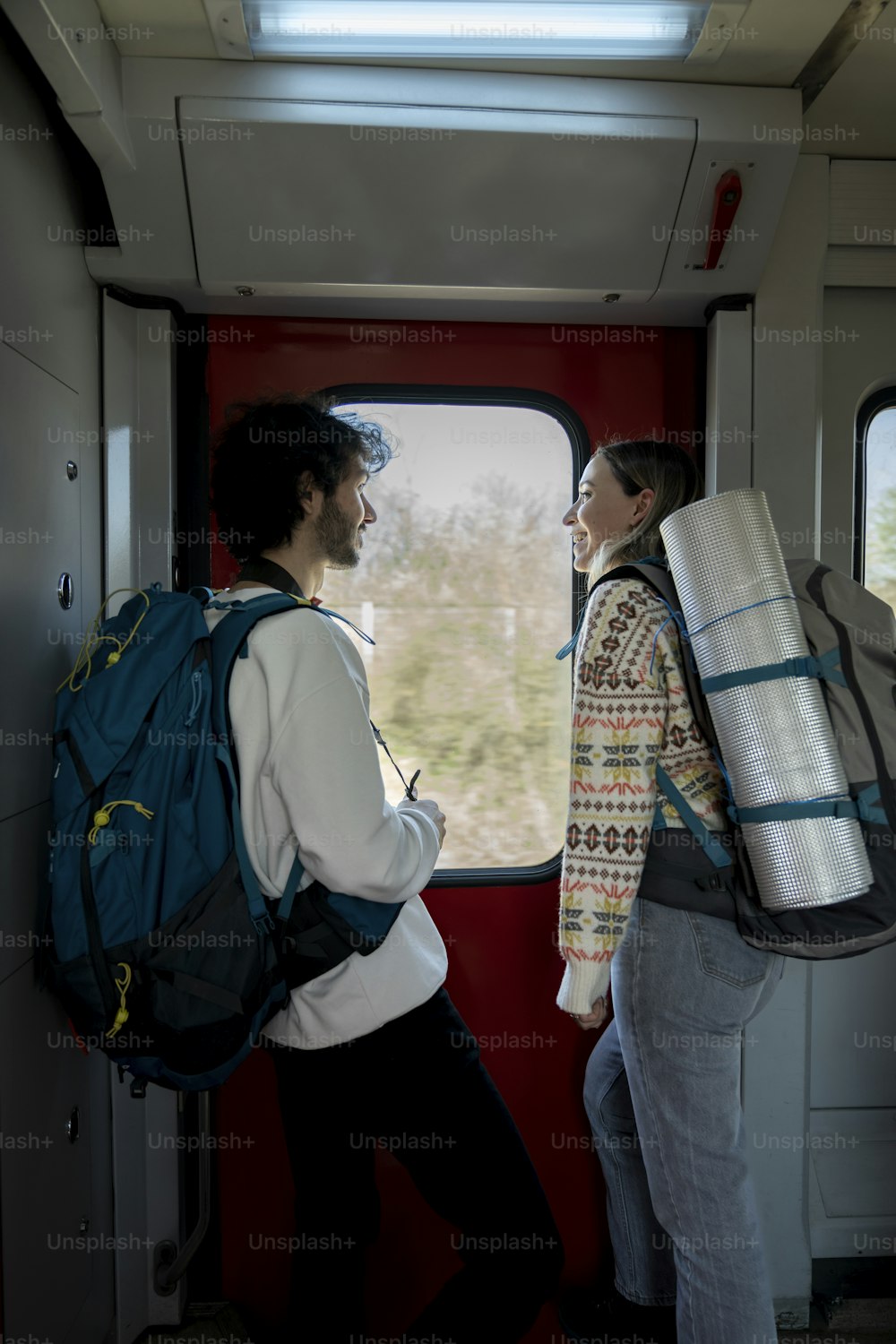a man and a woman standing on a train looking out the window