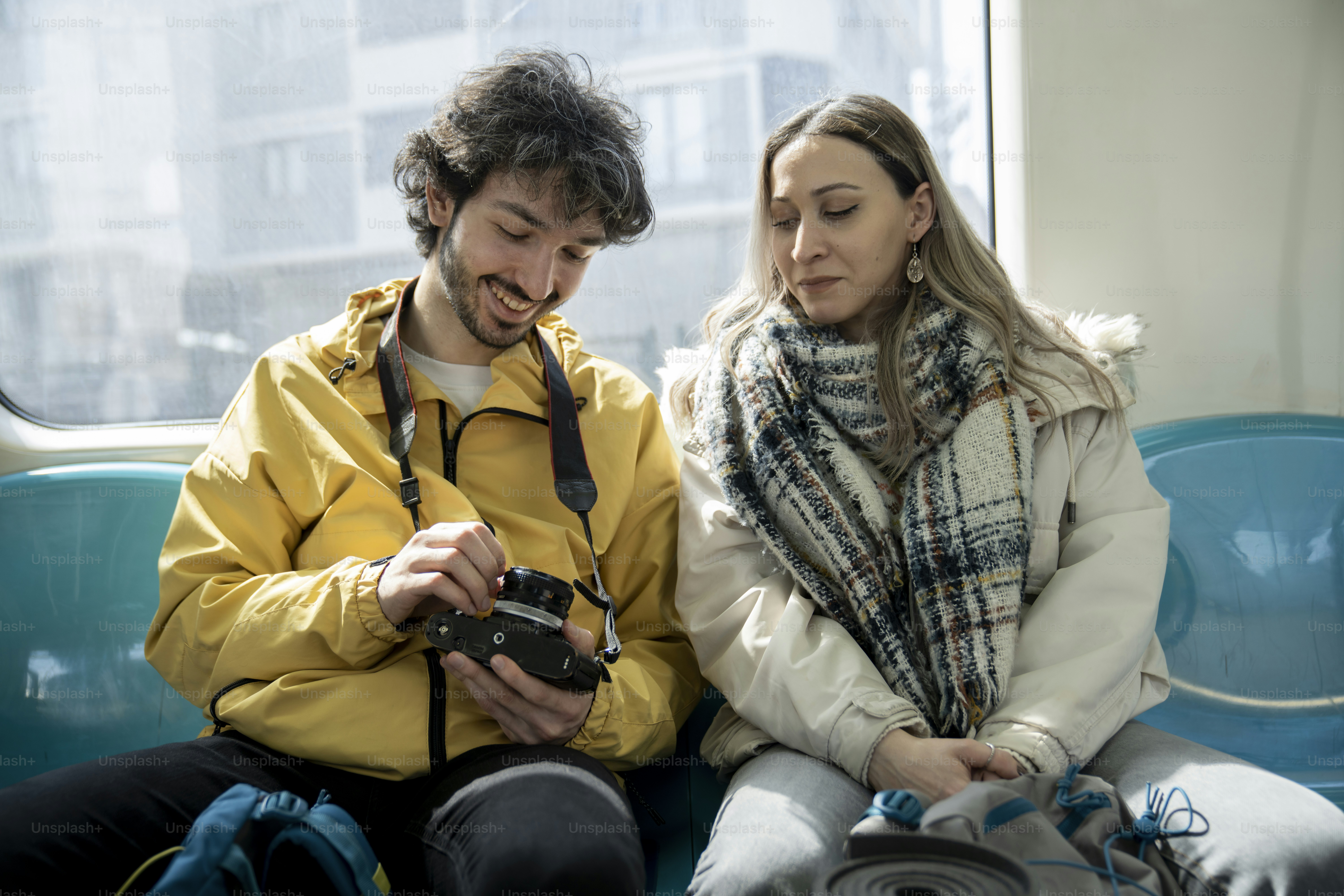 a man and a woman sitting on a bus looking at a cell phone