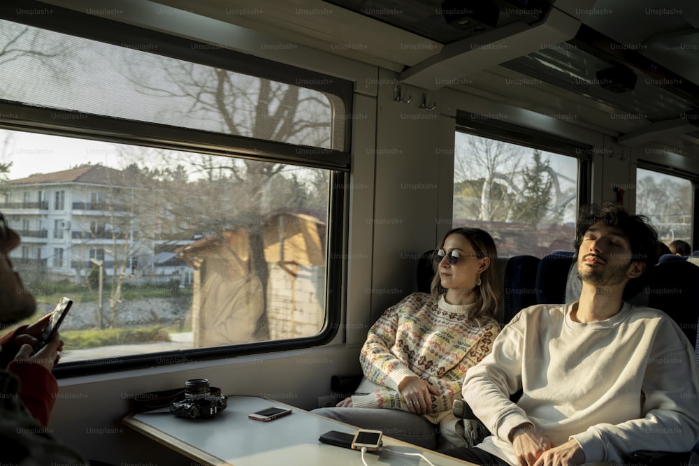 a man and a woman sitting on a train looking out the window