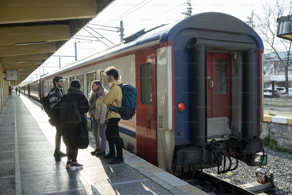 um grupo de pessoas em pé em uma plataforma ao lado de um trem