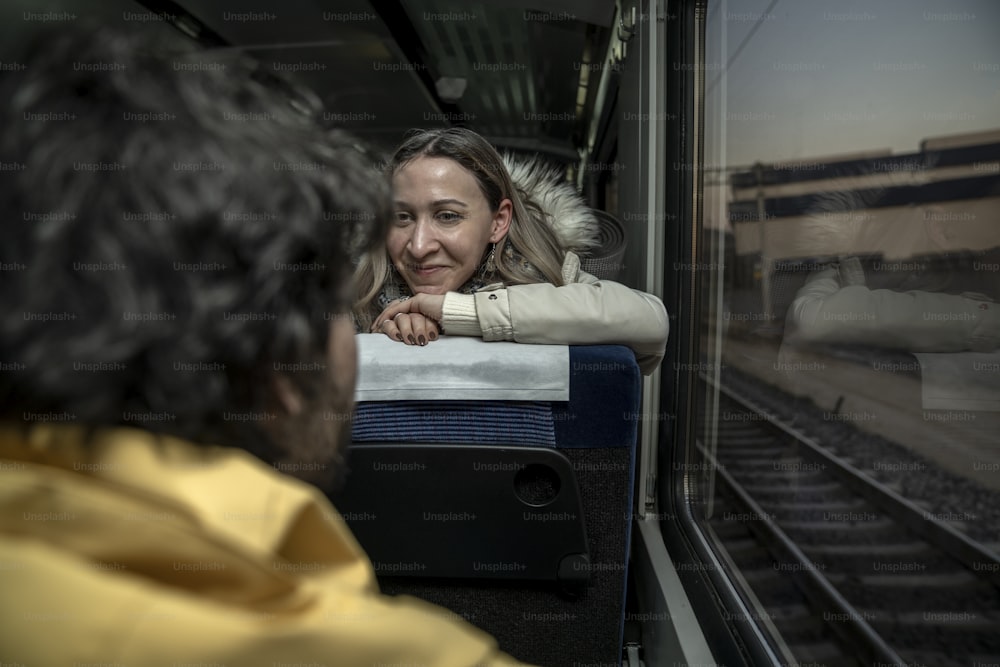 Una donna seduta su un treno che guarda fuori dal finestrino