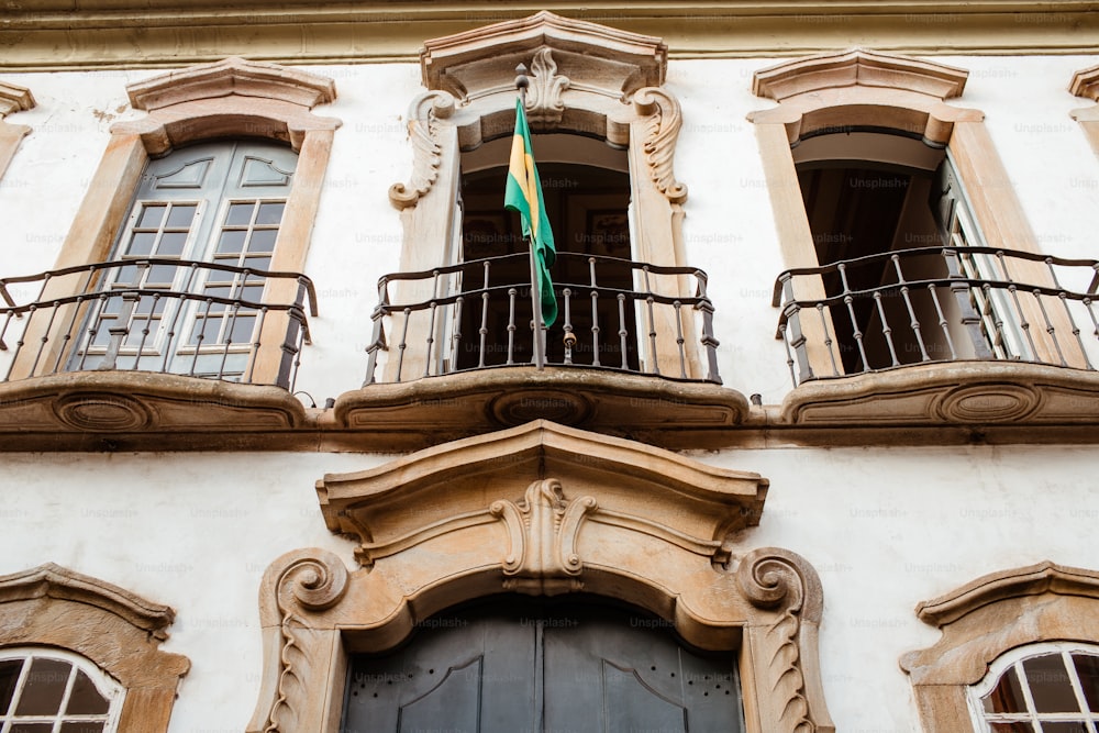 Un edificio con dos balcones y una bandera verde