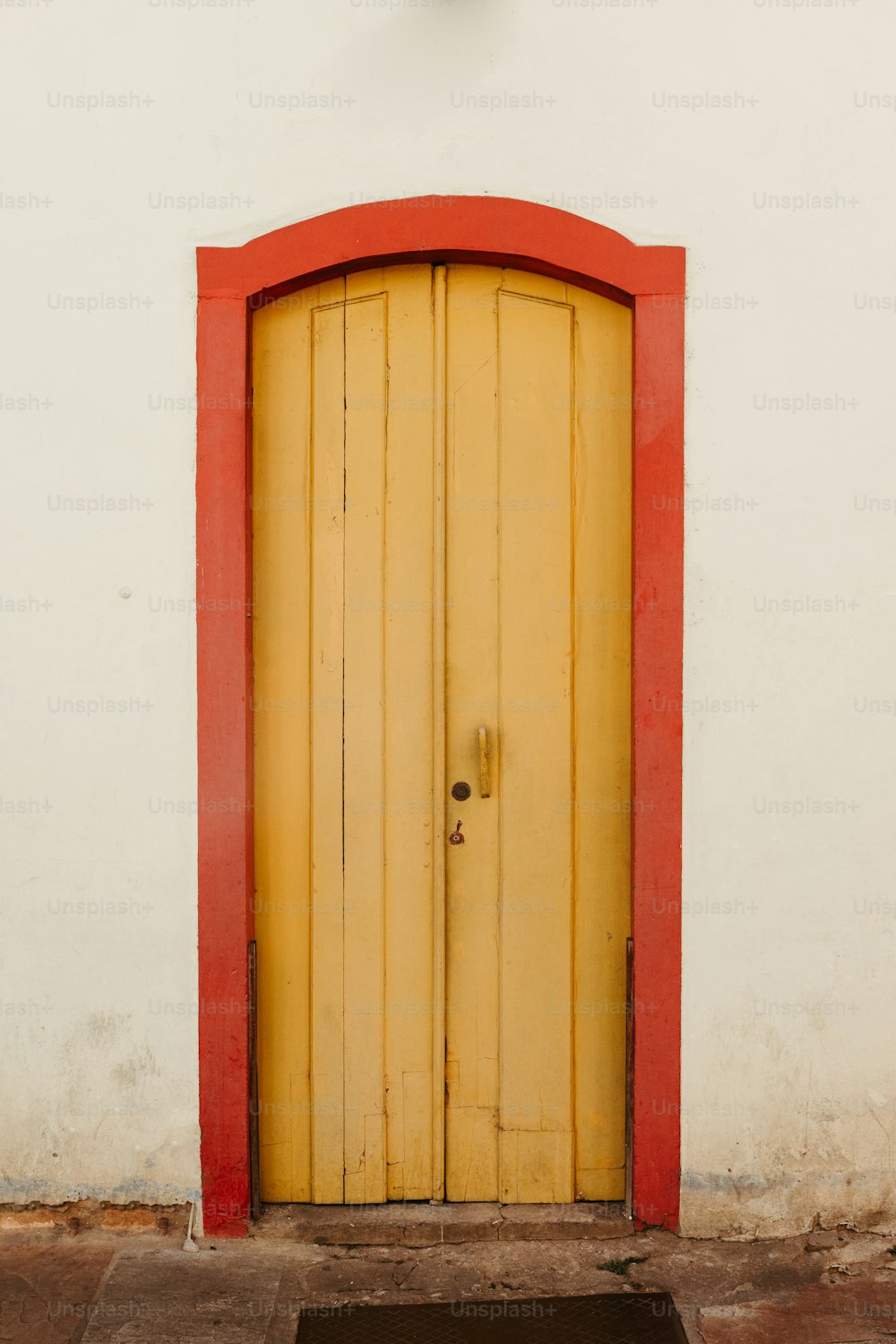 a yellow door with a red frame on a white wall