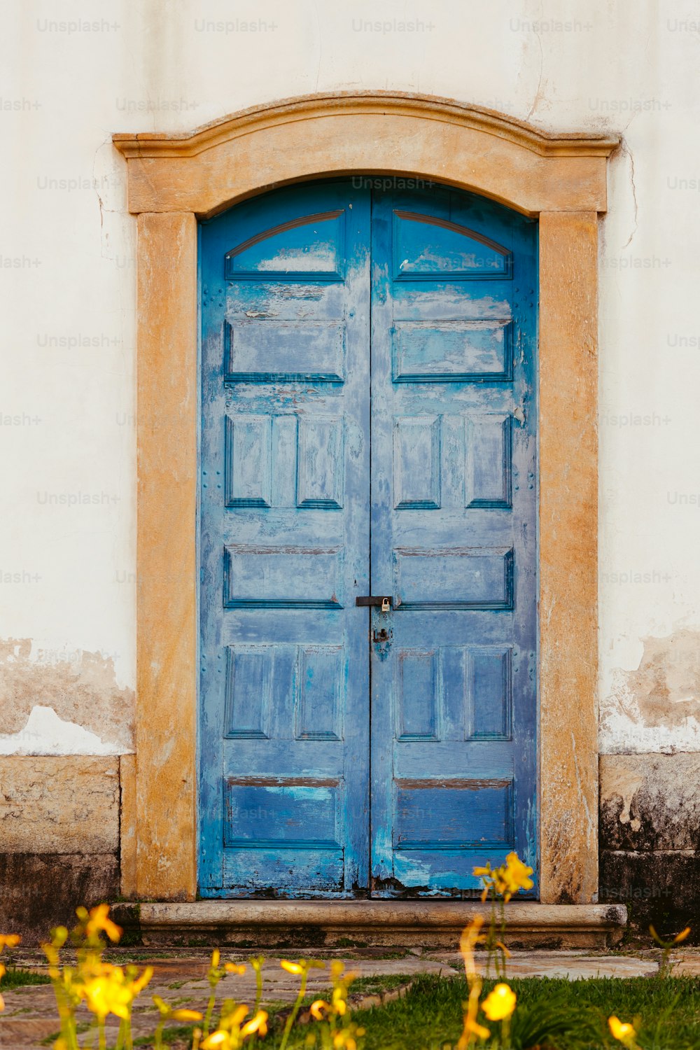 Una puerta azul con flores amarillas frente a ella