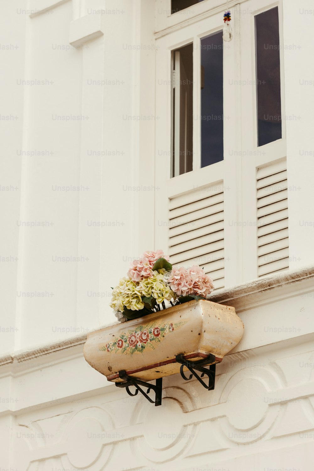 a white building with a flower box on the ledge