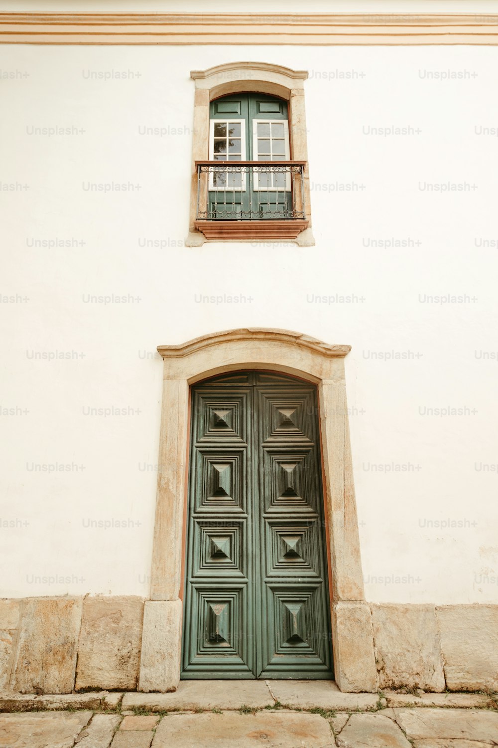 a green door with a window on a white building