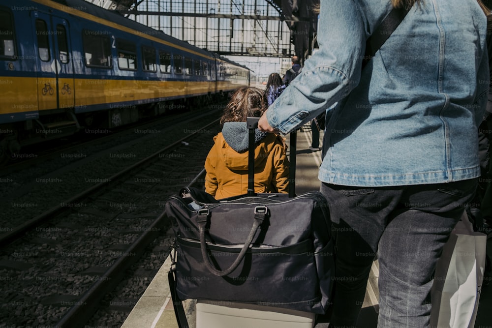 a woman pulling a child in a suitcase on a train platform