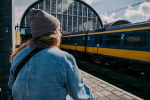 a woman standing on a platform looking at a train