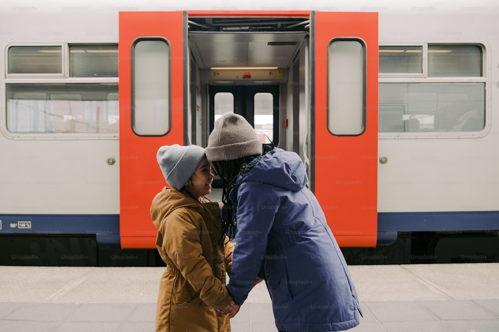 a couple of kids standing next to a train