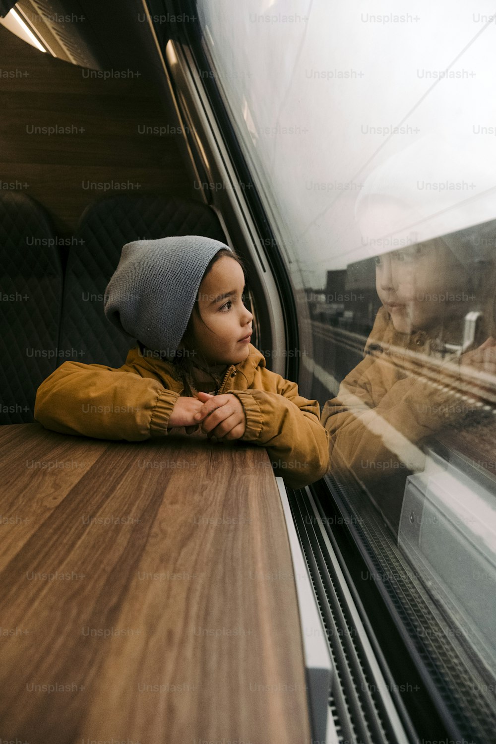 a little girl looking out the window of a train