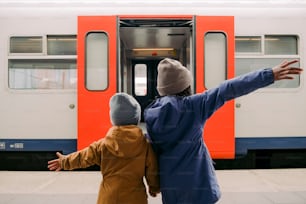 a woman and child standing in front of a train
