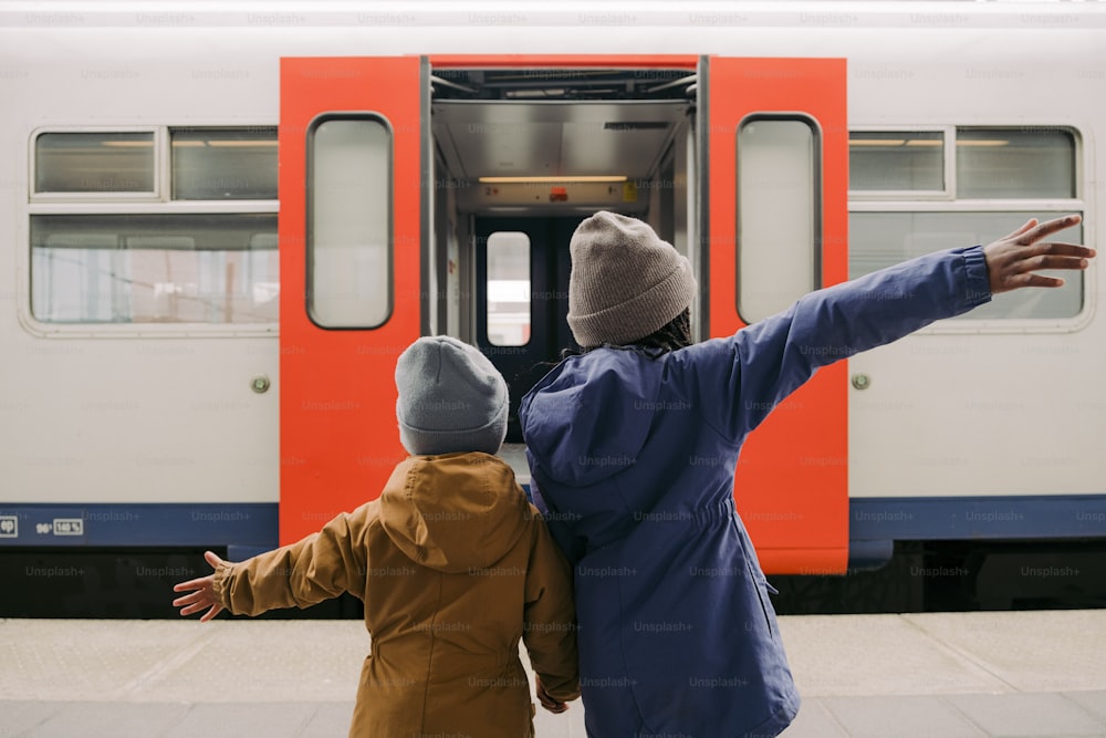 a woman and child standing in front of a train