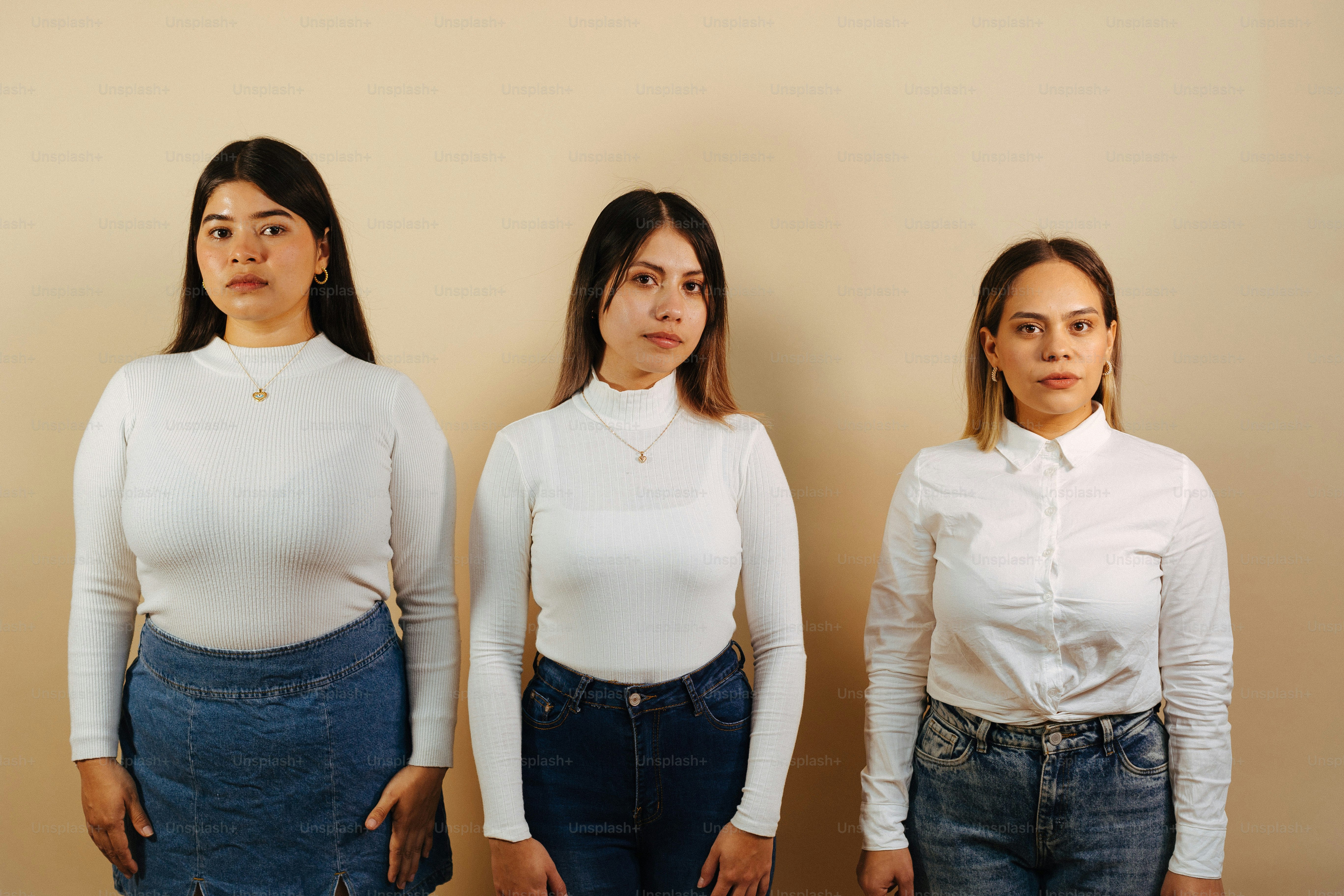 three women standing next to each other in front of a wall