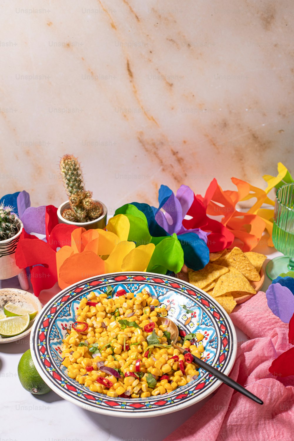 a bowl of corn sits on a table next to a plate of tortilla