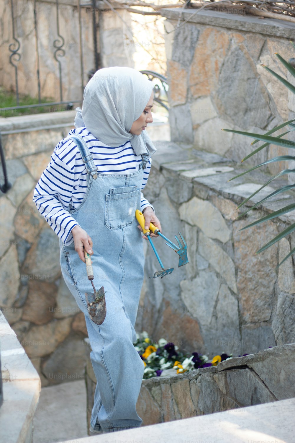 a woman in overalls and a headscarf holding a banana
