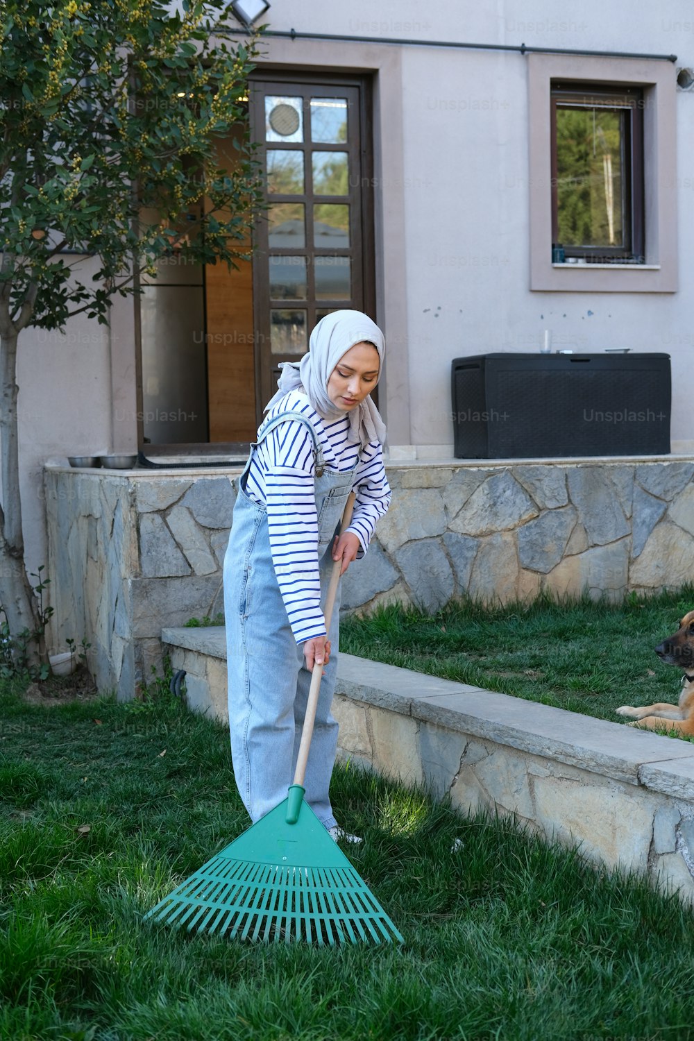 a woman in a headscarf is cleaning the grass