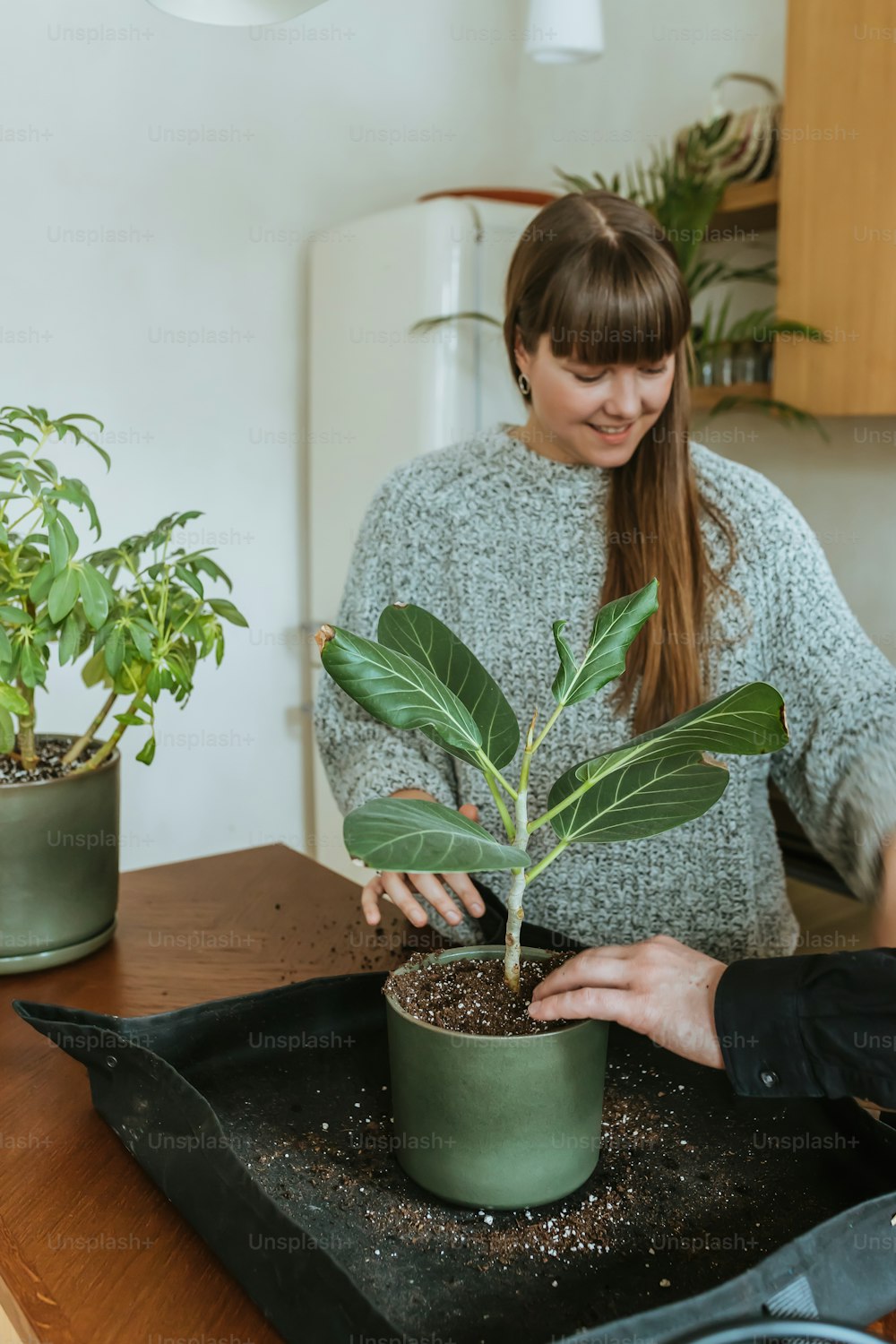 a woman holding a potted plant on top of a wooden table