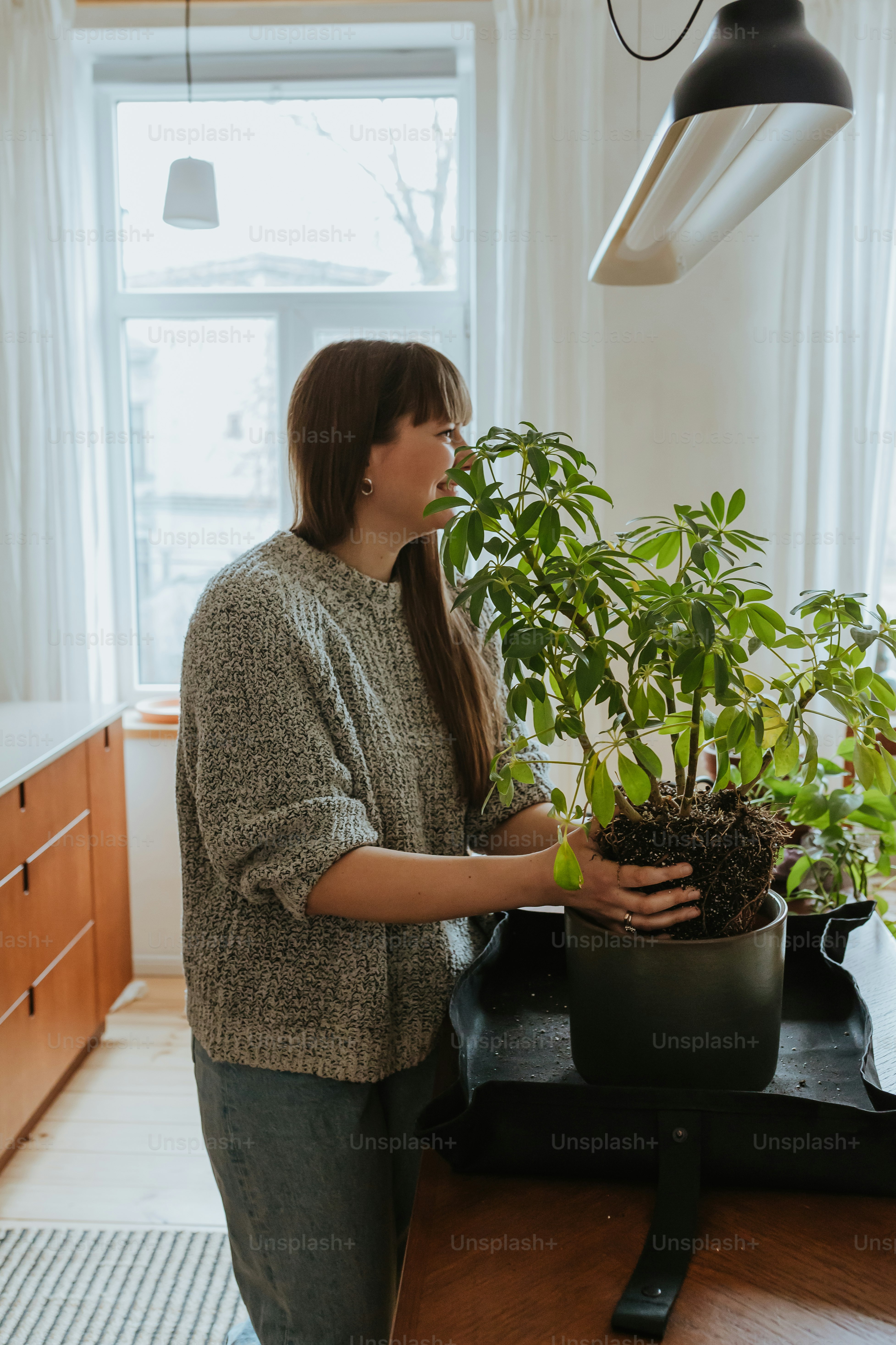 uma mulher que segura um vaso de planta em uma cozinha