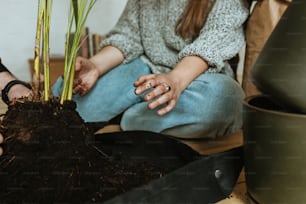 a woman sitting on the floor next to a potted plant