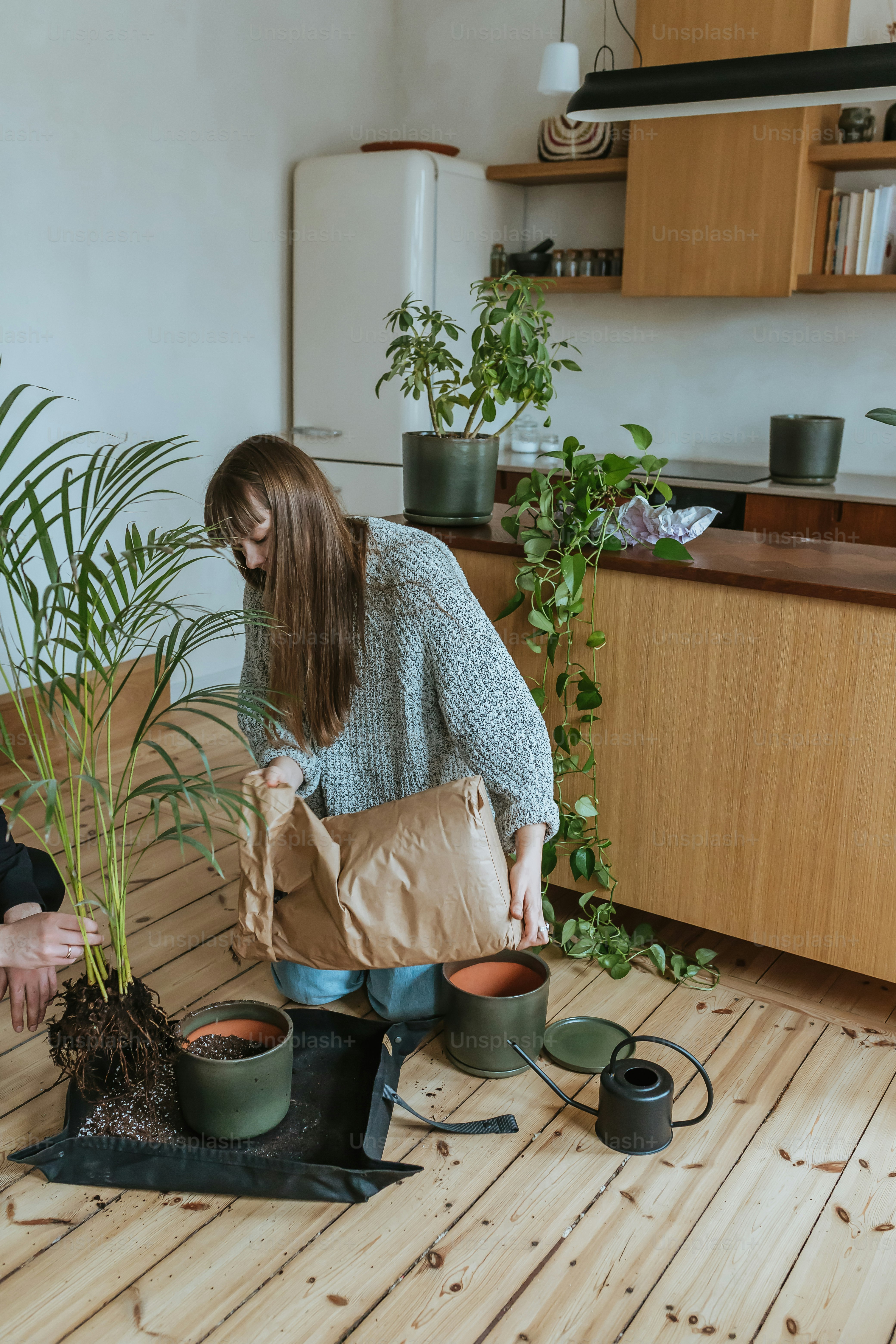 a woman holding a brown paper bag over a potted plant