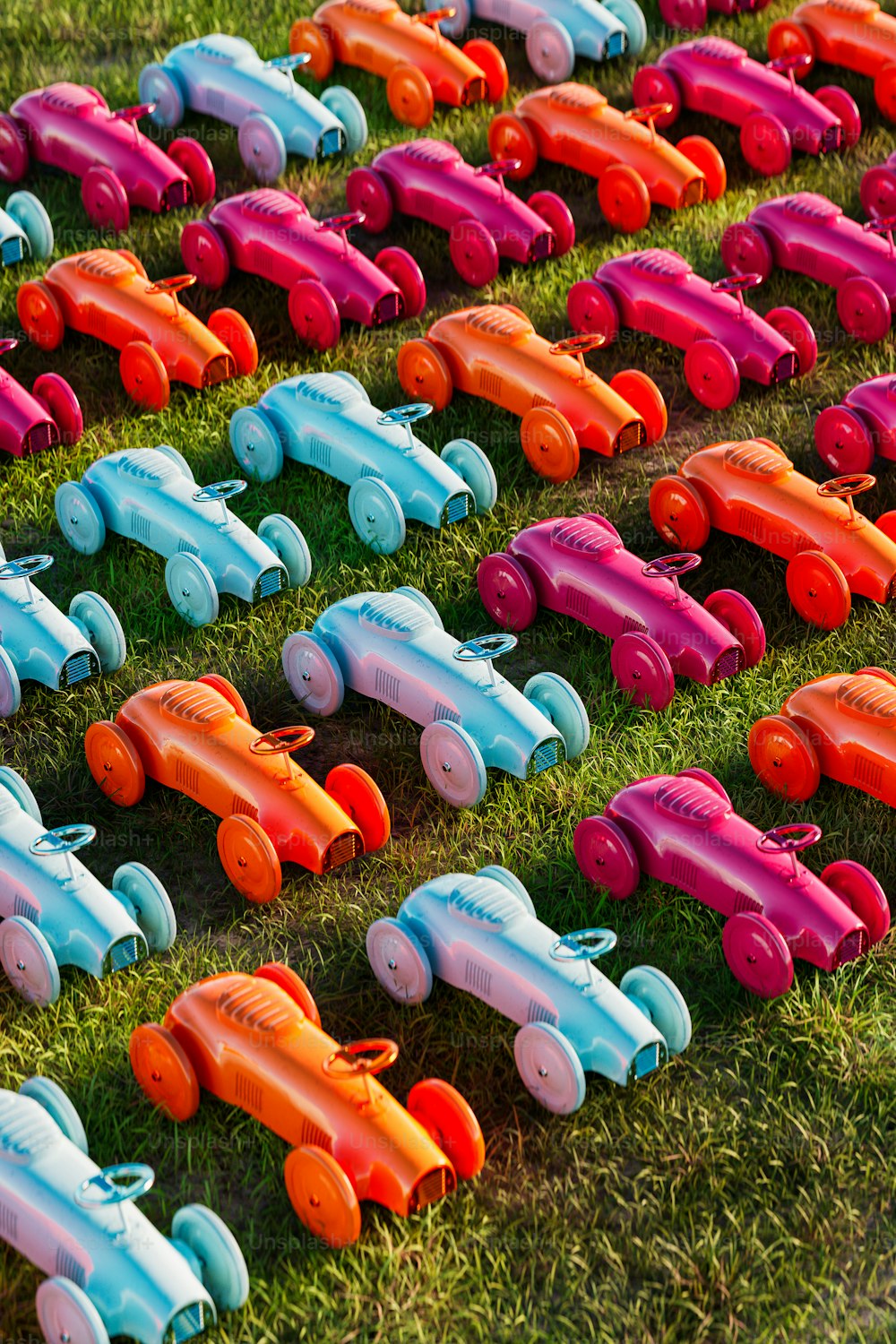 a row of toy cars sitting on top of a lush green field