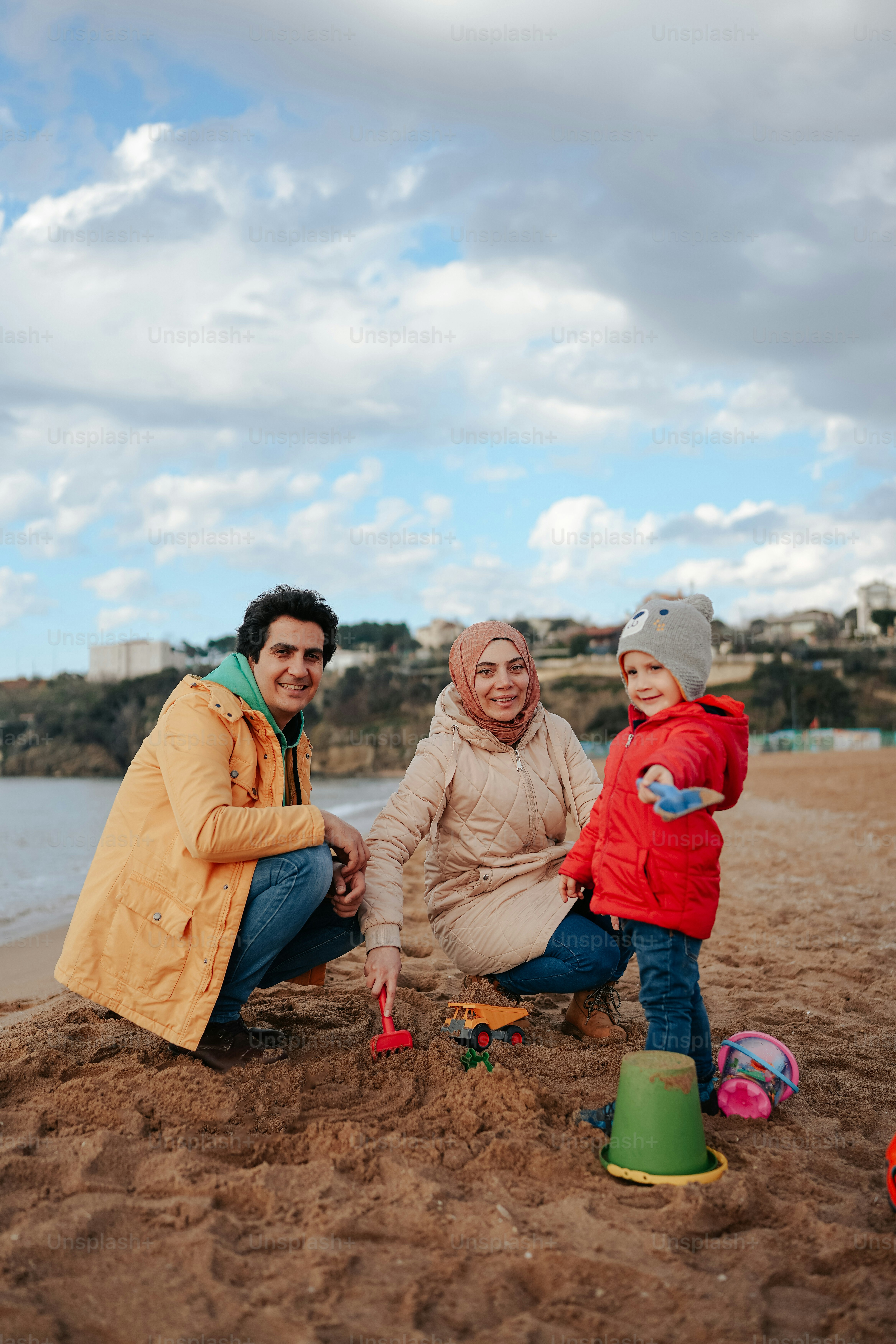 Ein Mann und zwei Kinder spielen im Sand