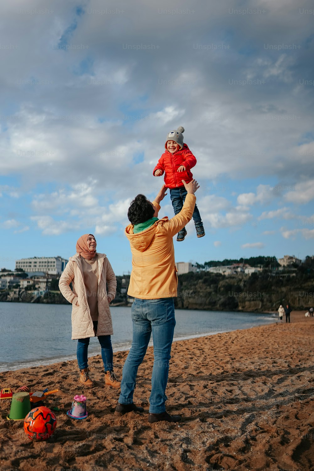 a man holding a child on his shoulders on the beach