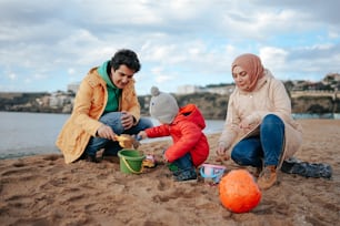Un hombre y una mujer jugando con un niño en la playa