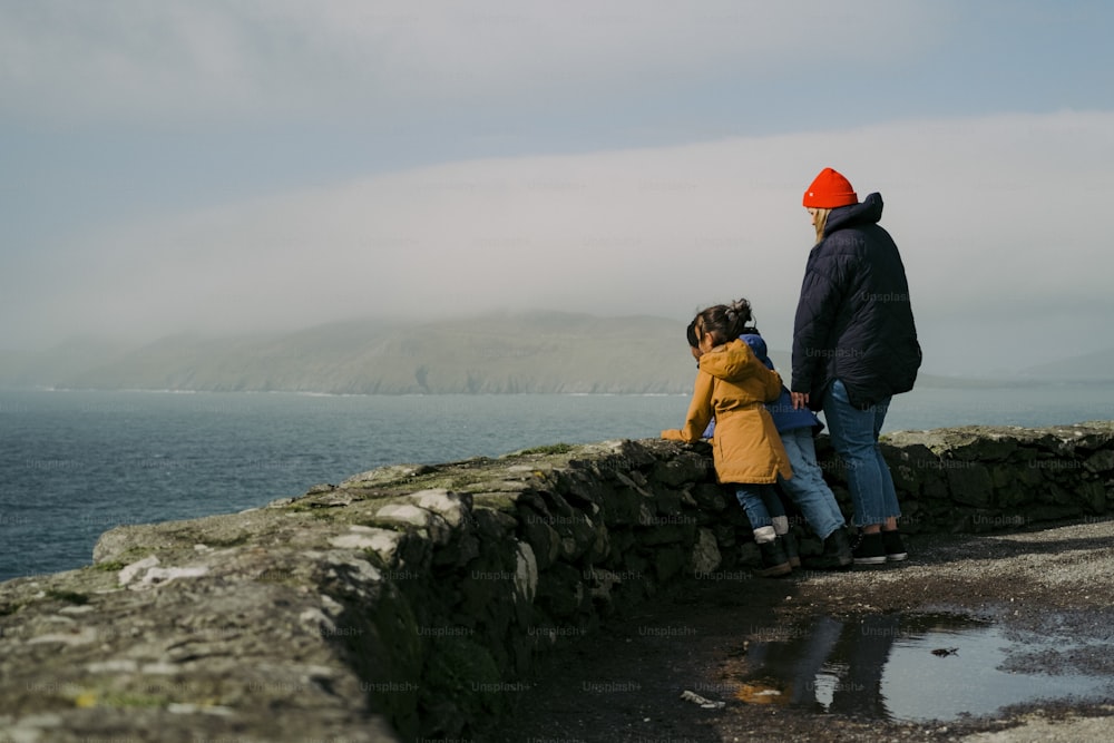 a man and a little girl standing on a stone wall