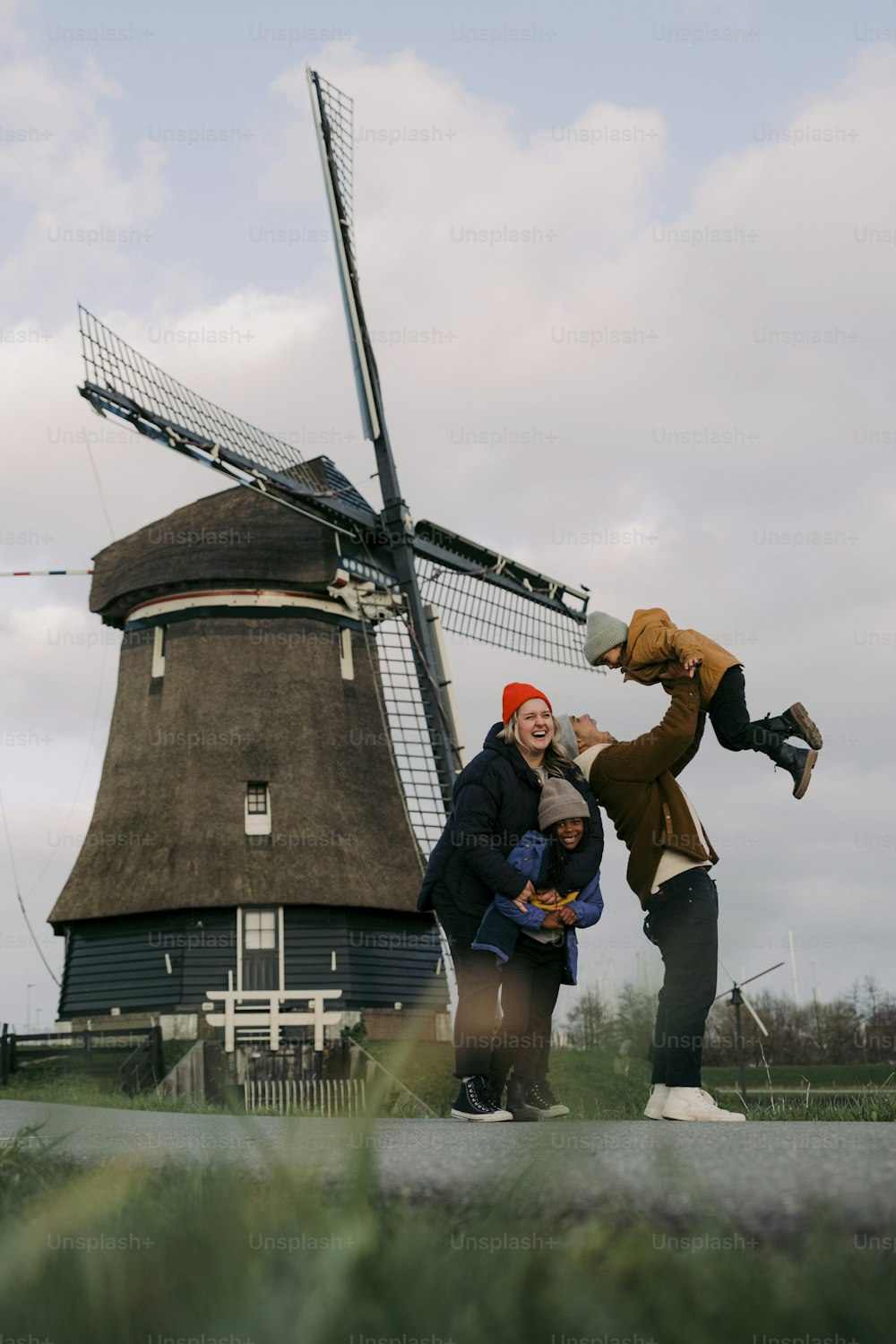 três pessoas em pé na frente de um moinho de vento