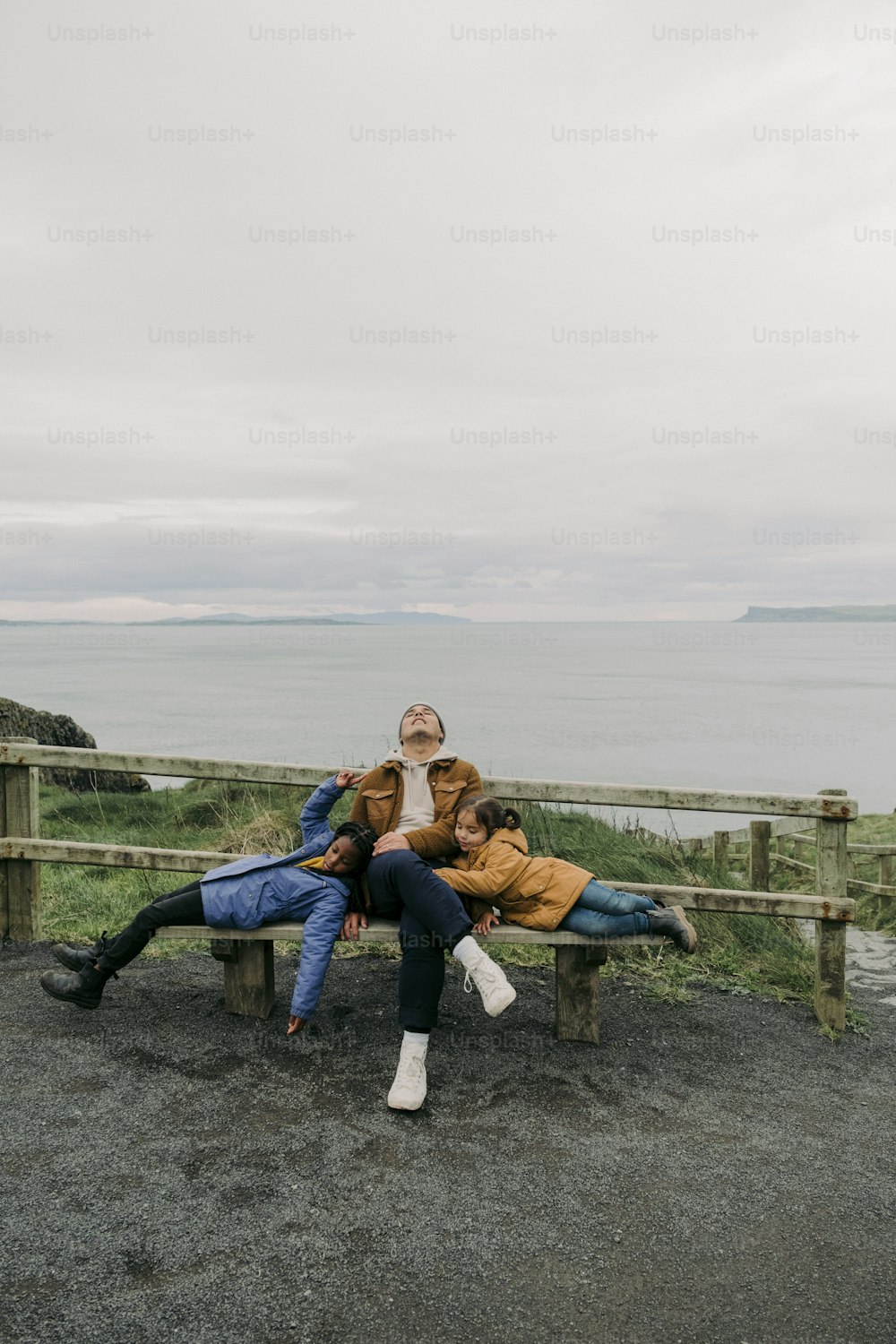 two people sitting on a bench near the ocean