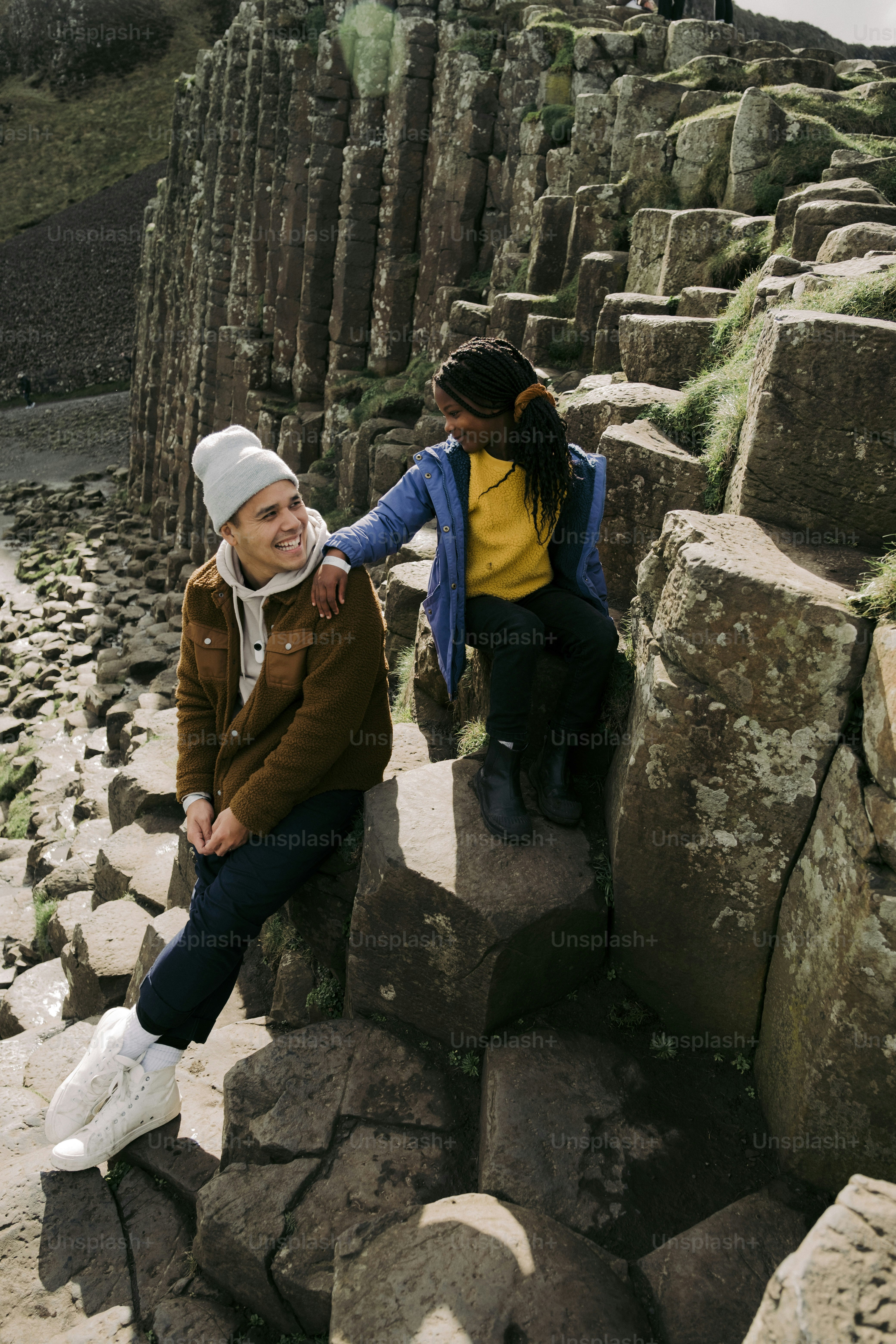 duas pessoas sentadas em rochas perto de um corpo de água