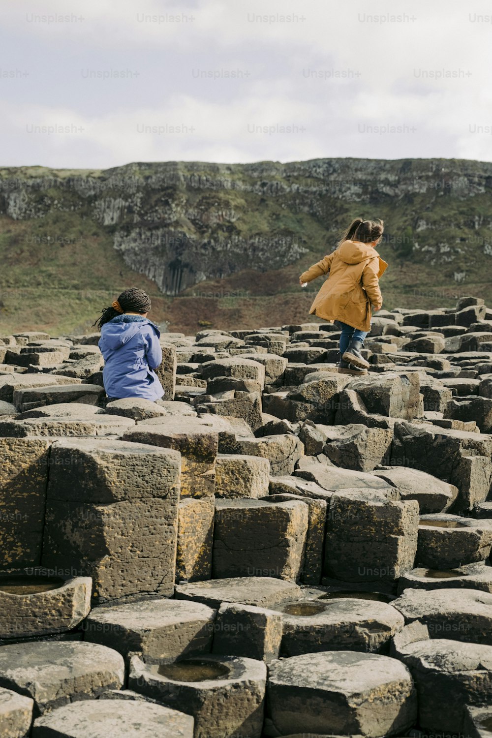 two children are sitting on a large rock formation