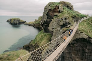a group of people crossing a rope bridge over a body of water