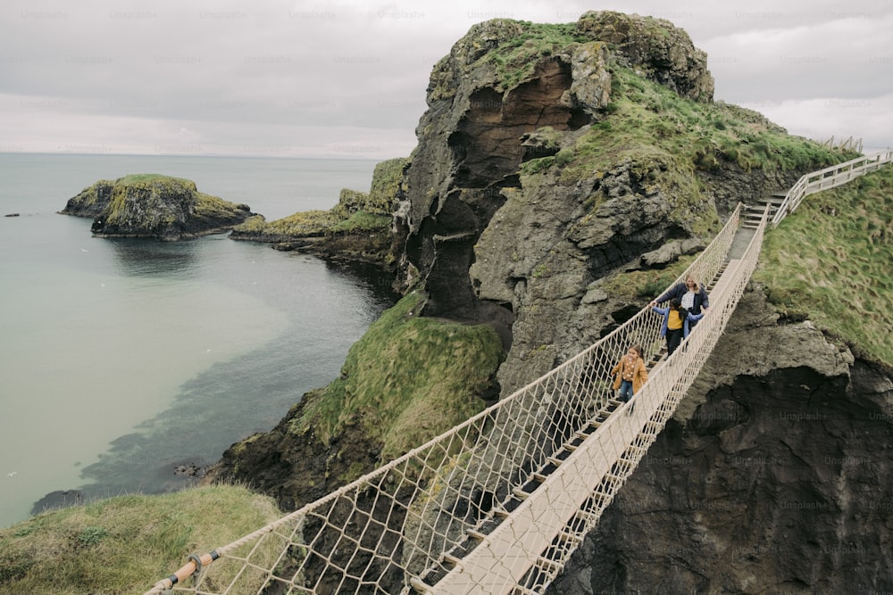a group of people crossing a rope bridge over a body of water