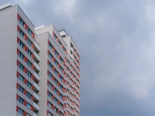 a tall white and red building next to a cloudy sky