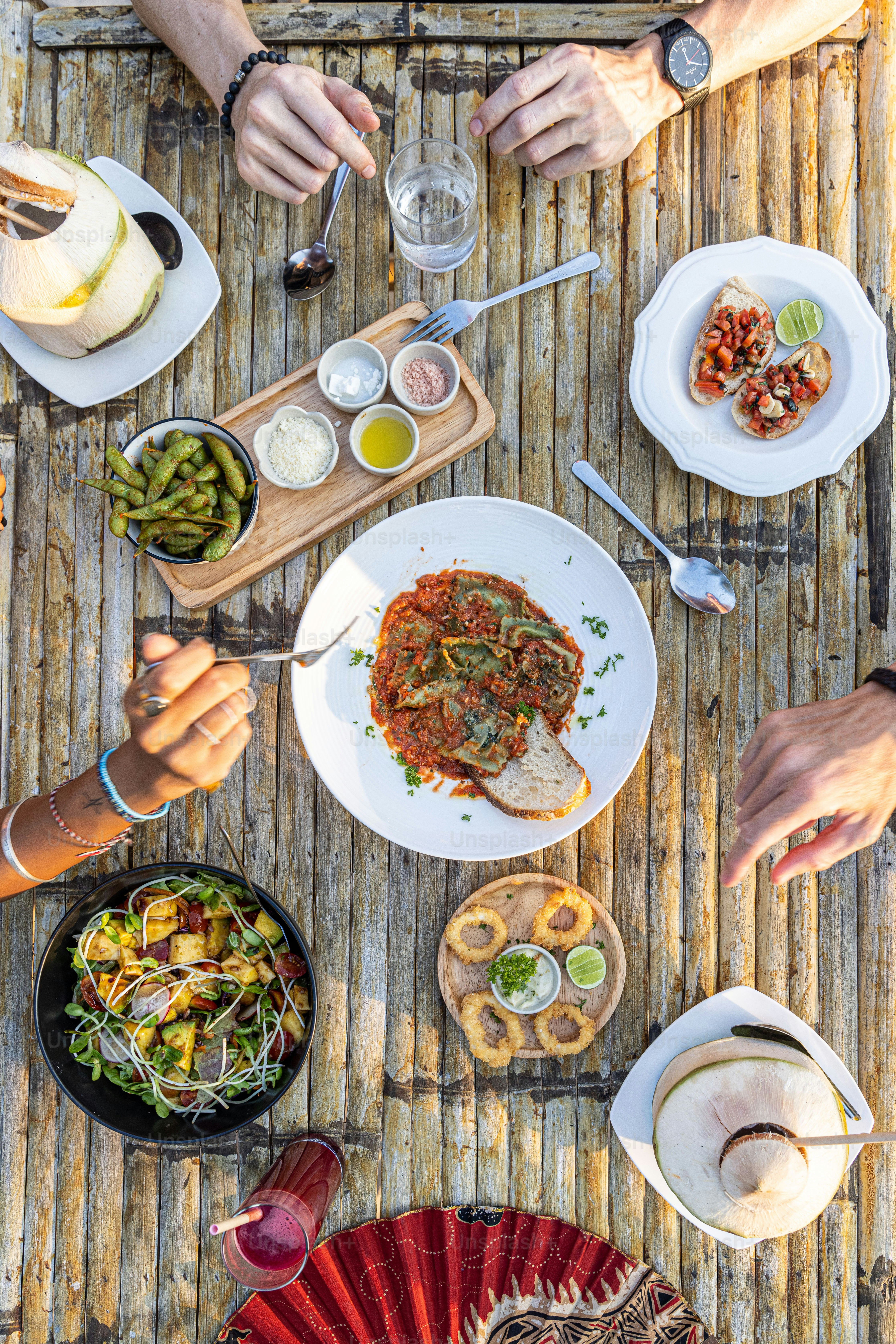 a group of people sitting at a table with plates of food