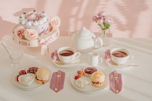 a table topped with plates of food and cups of tea