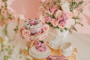 uma mesa coberta com um bolo ao lado de um vaso cheio de flores