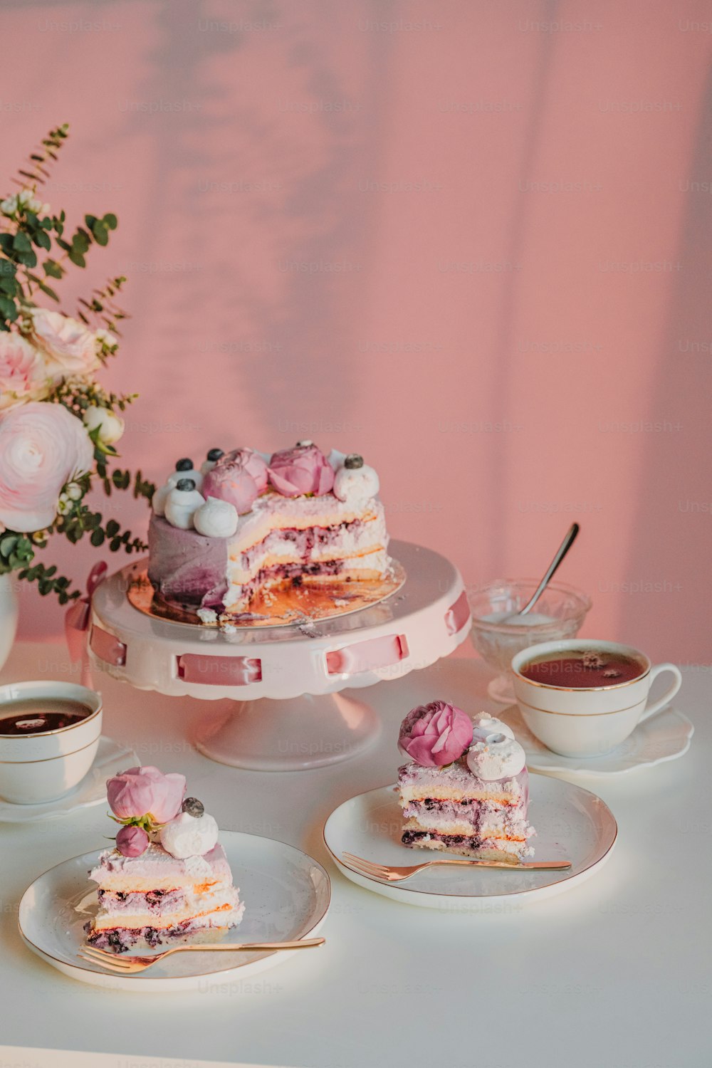 uma mesa coberta com um bolo e xícaras de café