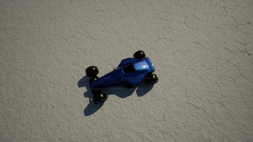 um carro de brinquedo azul sentado em cima de uma praia de areia