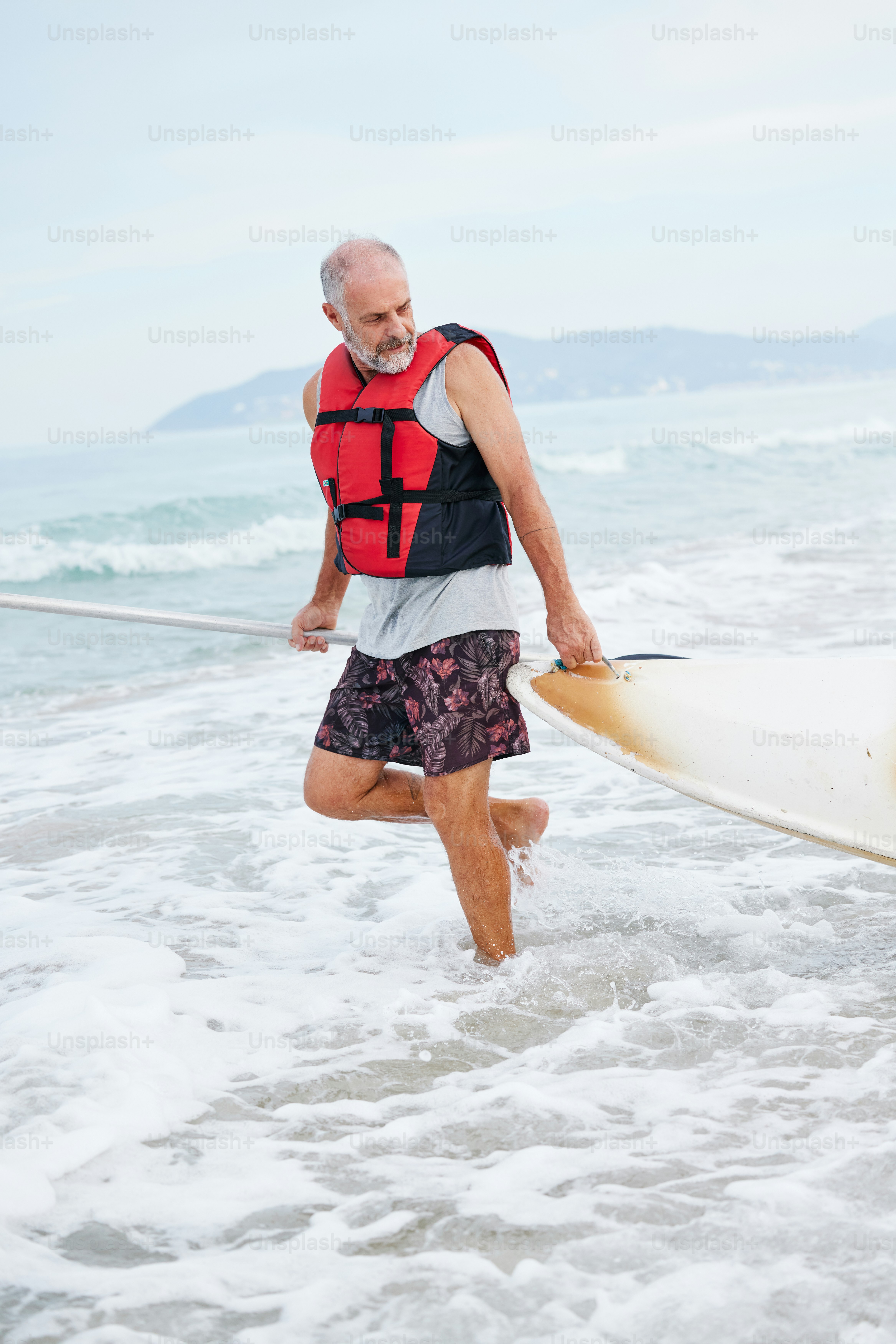 a man walking into the ocean with a surfboard