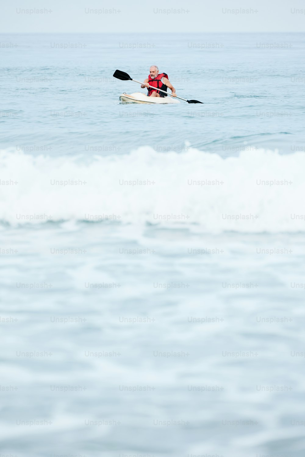 Un hombre montando un kayak en la cima de una ola en el océano