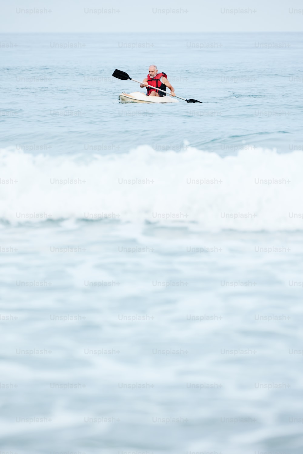a man riding a kayak on top of a wave in the ocean