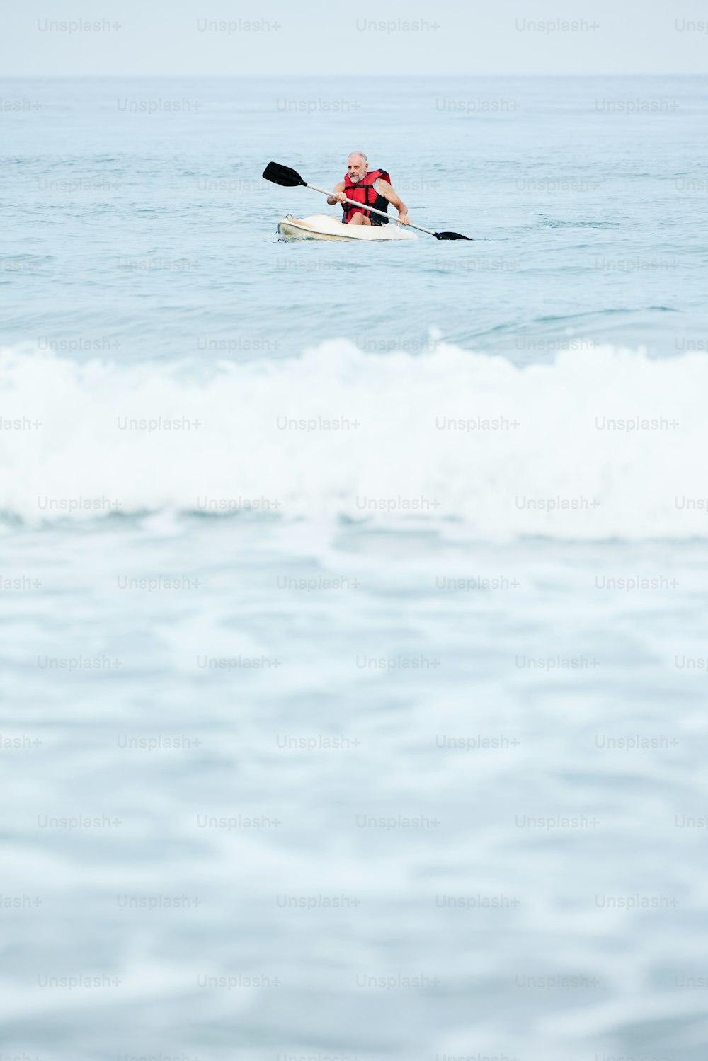 a man riding a kayak on top of a wave in the ocean